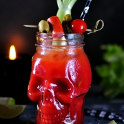 deadhead Bloody Mary cocktail in glasses-skull with celery sticks, pink salt, lime and canapes from canned vegetables