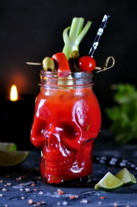 deadhead Bloody Mary cocktail in glasses-skull with celery sticks, pink salt, lime and canapes from canned vegetables